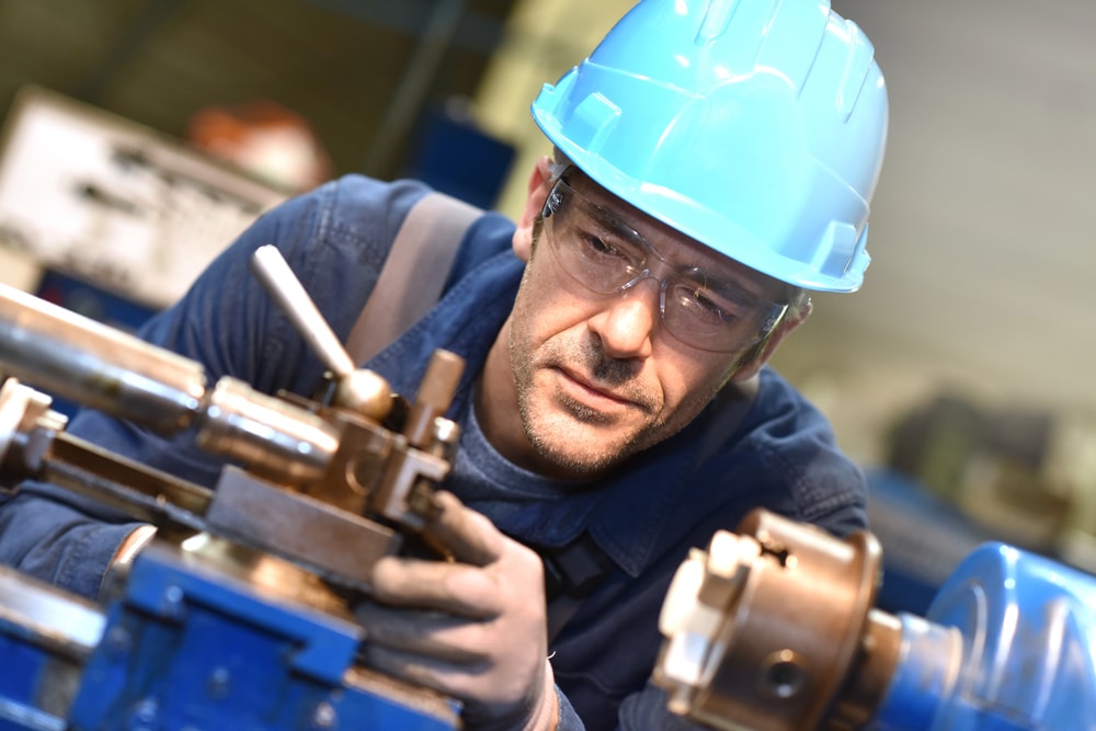 Работник в автосервиз със синя предпазна каска и прозрачни предпазни очила