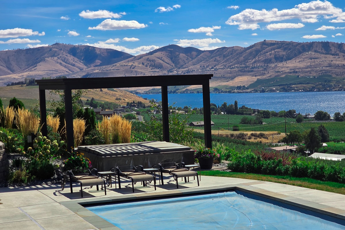 Hot tub pergola installed poolside overlooking a lake.