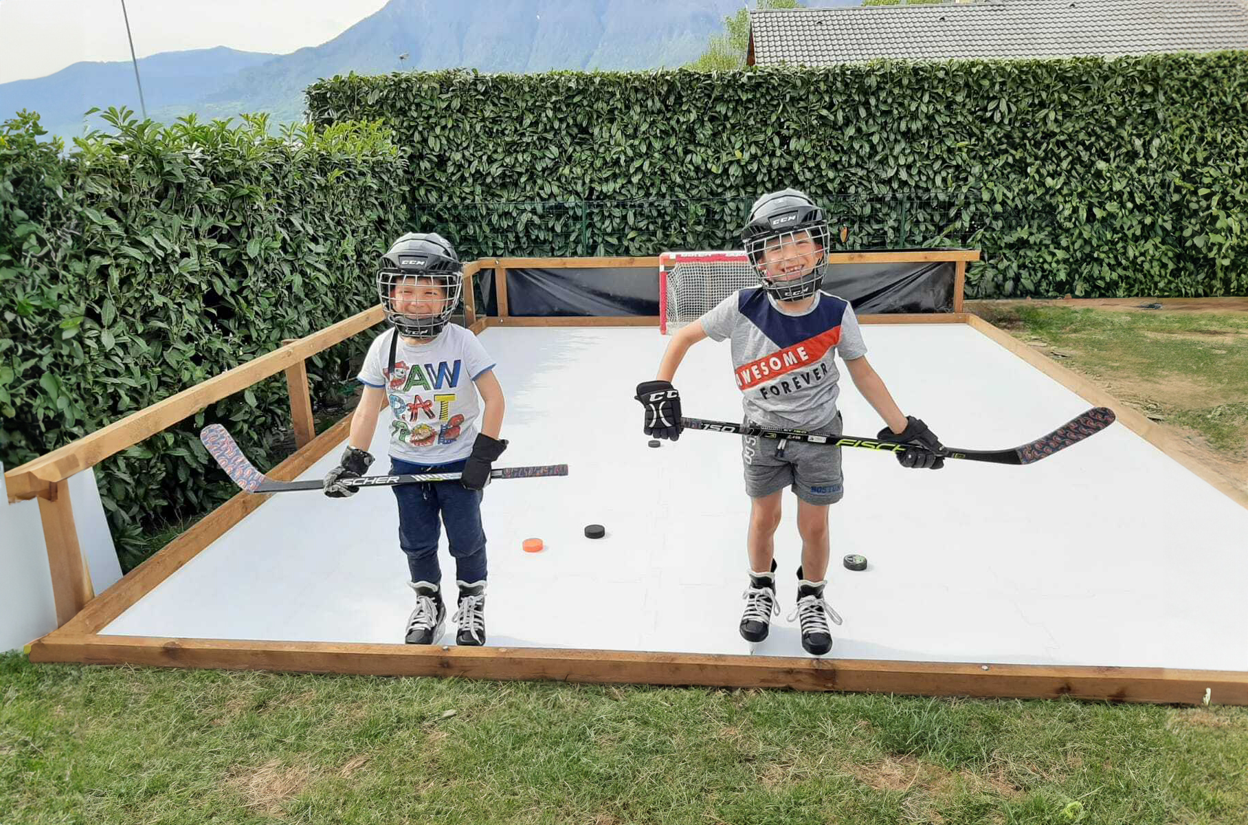 Two boys with their ice hockey equipment on synthetic ice rink