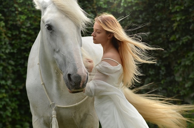 woman in white dress next to a white horse