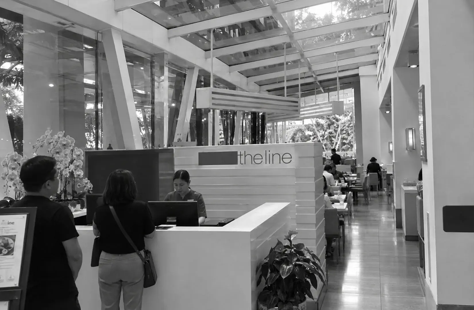 Modern restaurant reception area with guests at the front desk.