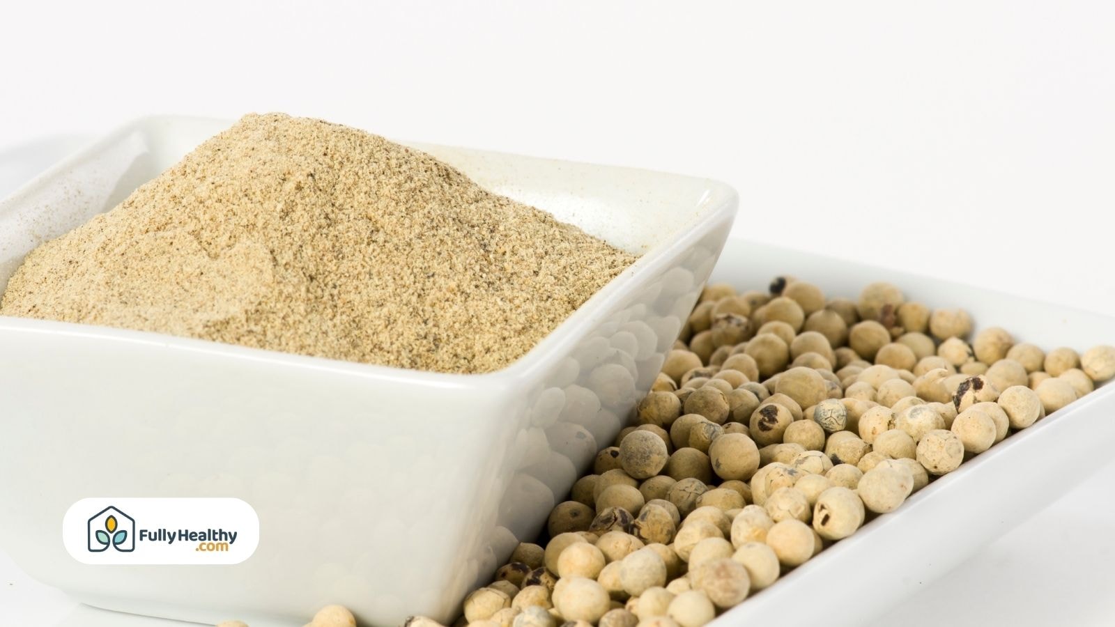 Ground white pepper and whole white peppercorns in a ceramic dish