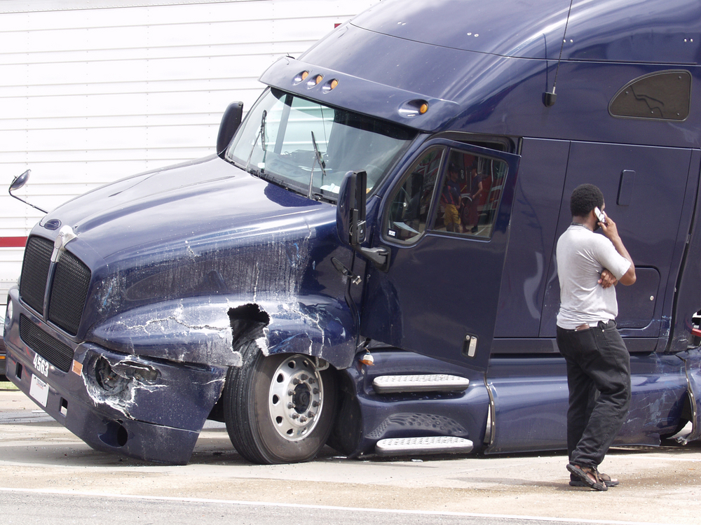 truck car accident on the road and a truck driver on the phone calling an accident lawyer 