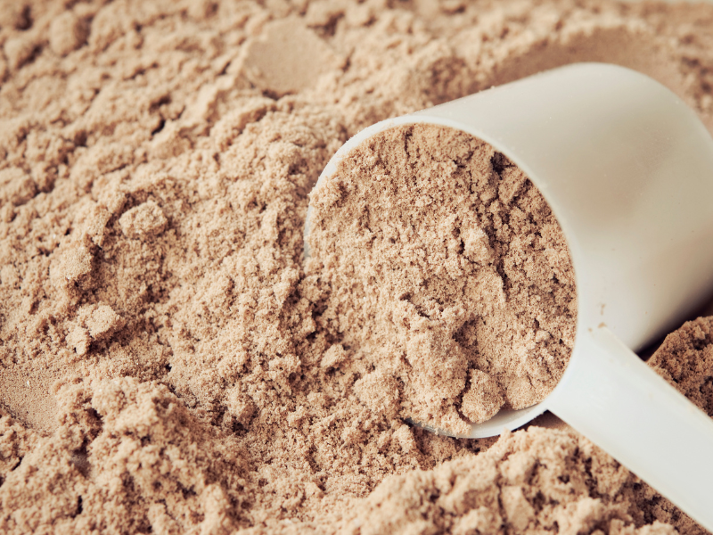 Picture of a scoop inside a tub of protein powder.