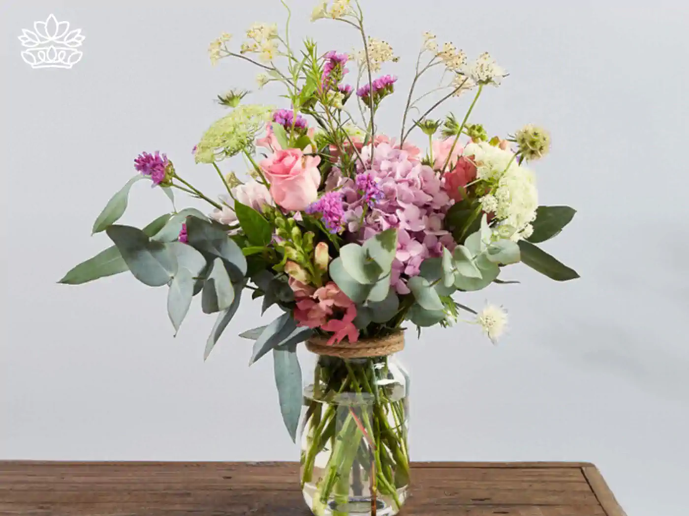 Elegant get well flower arrangement in a clear vase, featuring soft pink roses, lush hydrangeas, and delicate white blooms, accented with eucalyptus leaves. Delivered with Heart. Fabulous Flowers and Gifts.