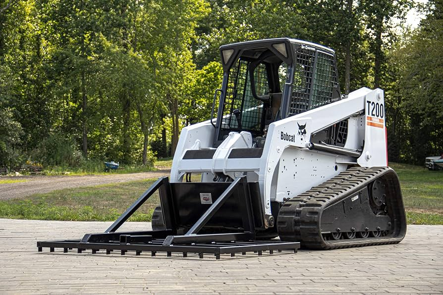 A skid steer with a landscape rake attachment leveling soil and debris