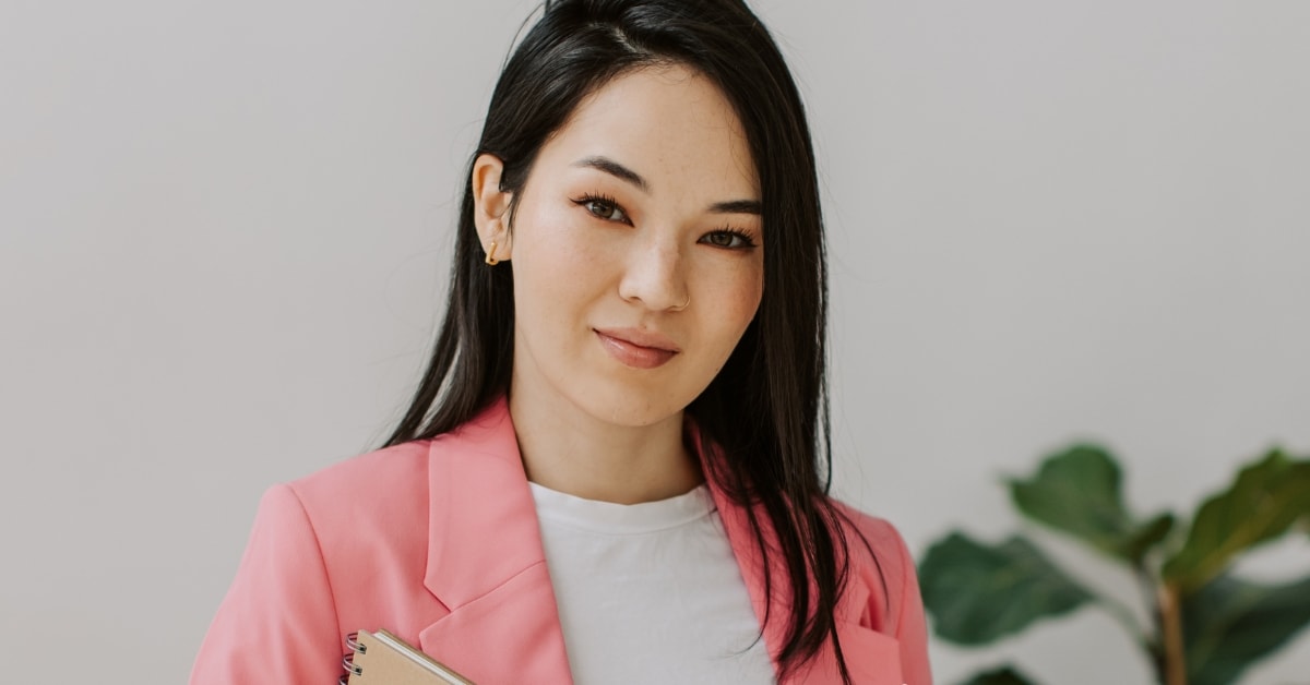 Young woman in a pink blazer holding a notebook, symbolizing professional CPA services.