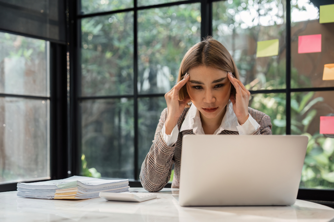 Stressed remote worker holding head in frustration at laptop, highlighting effects of missed recognition.