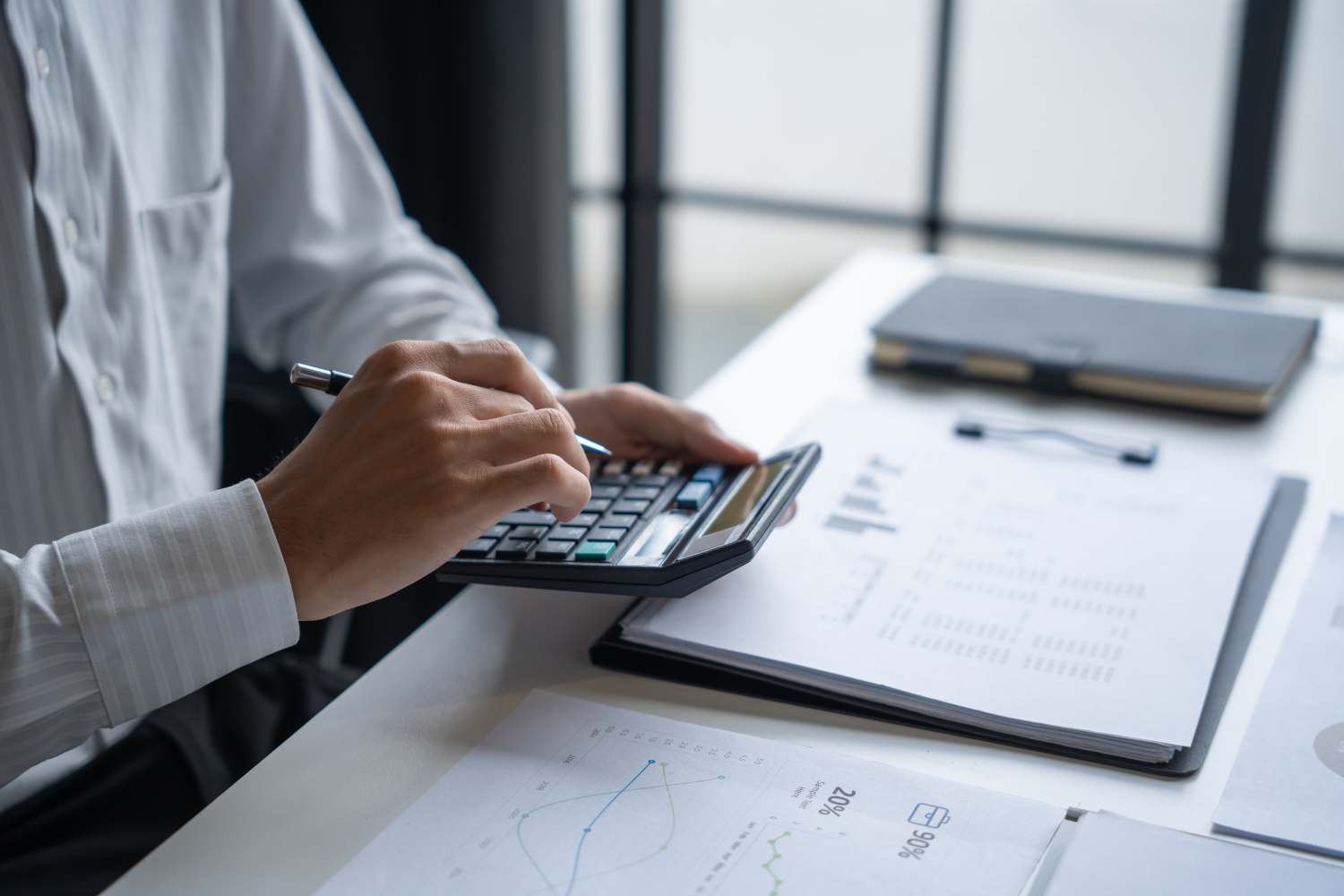 Person is using a calculator while sitting at a desk.