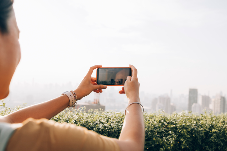 Young woman taking a selfie with a city stretched out in front of her.