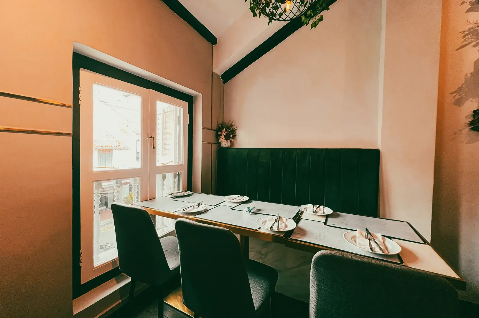 Eye-level shot of a cozy halal restaurant corner with a window-side table, cushioned bench seating, neatly set plates, and soft natural light creating an intimate dining setting.