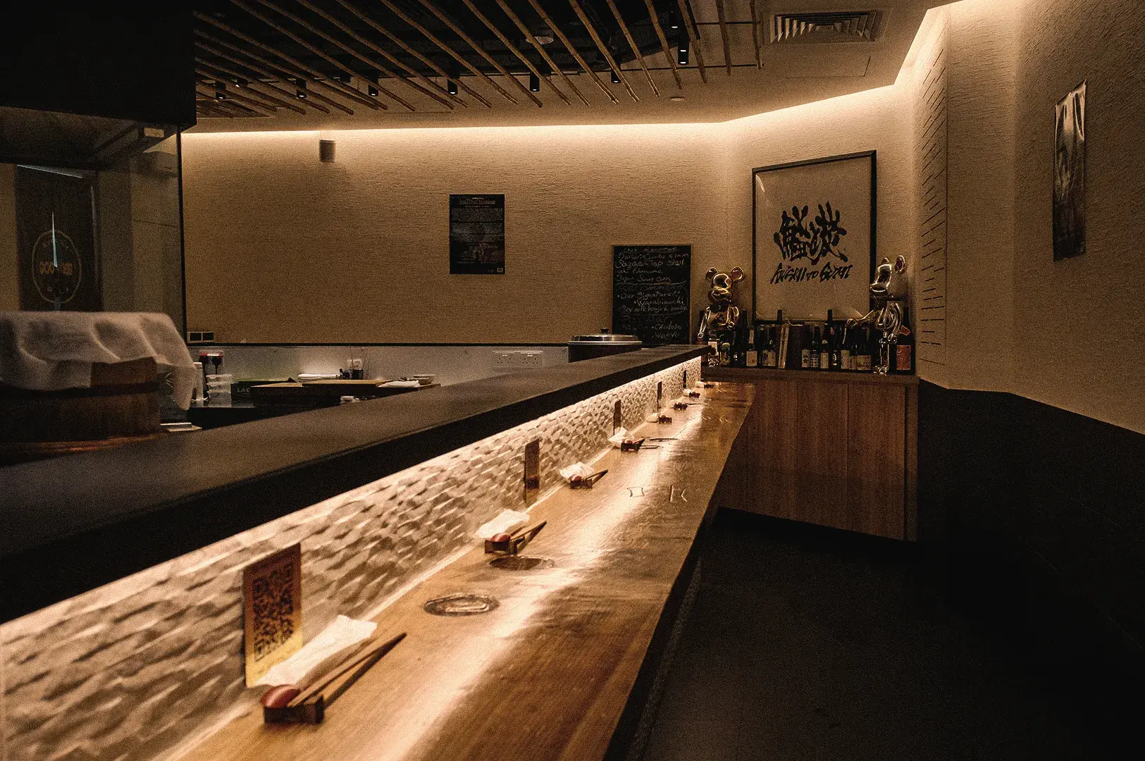 A wide perspective shot captures the warmly lit, modern standing counter interior designed for solo diners at Sushi to Sumi Japanese restaurant.