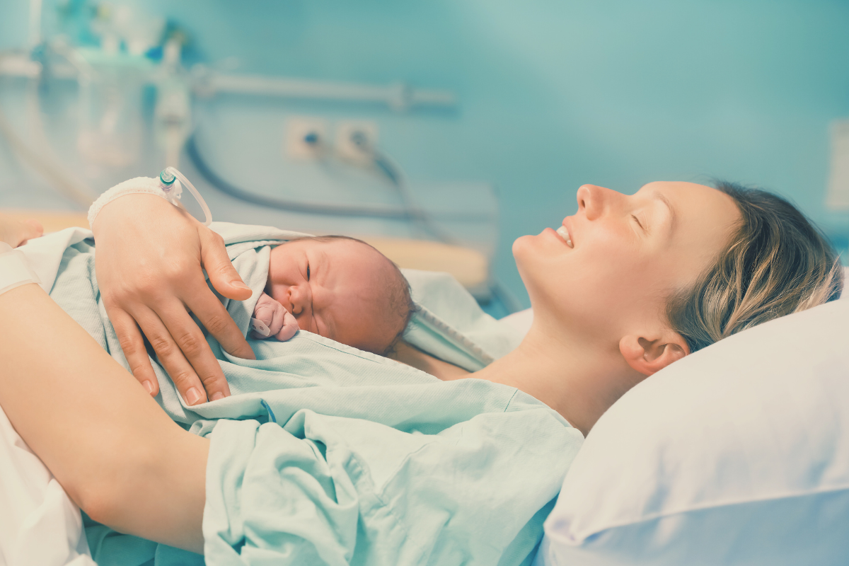 Mom holding newborn while laying in hospital bed