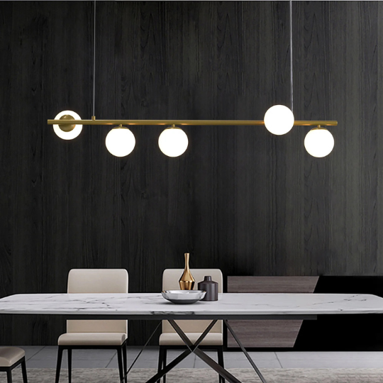 Modern linear chandelier with five globe lights hanging above a marble dining table in a contemporary dining room.