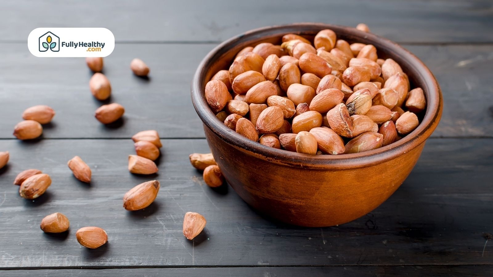 Bowl of whole peanuts on dark wooden table with scattered shells