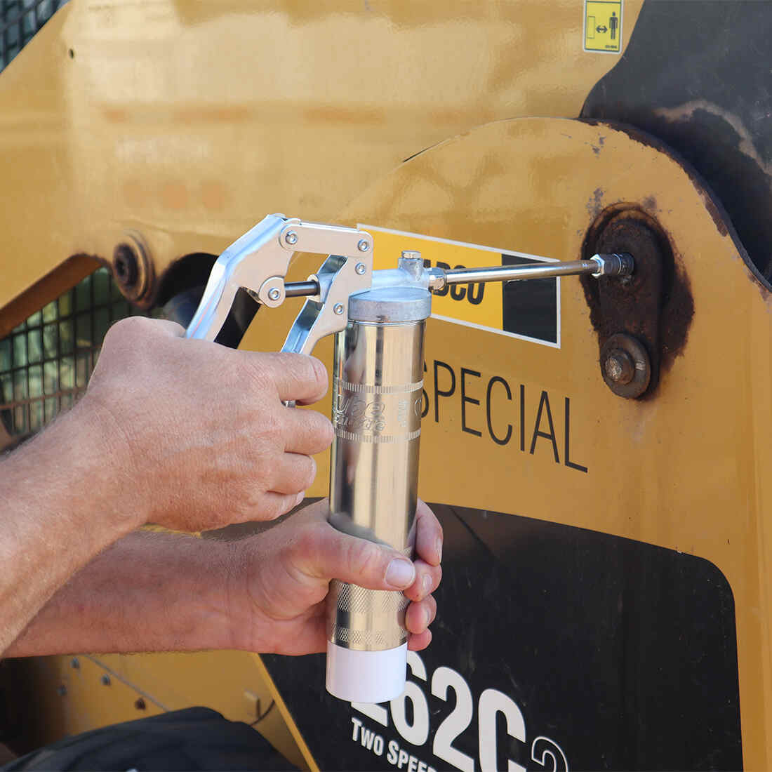 Grease gun being used in a cat tractor