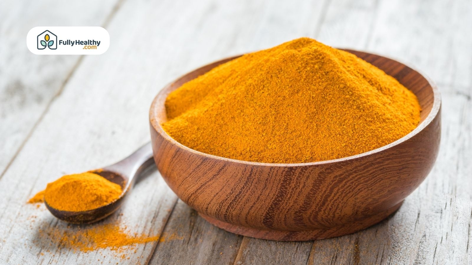 Turmeric powder in a wooden bowl and spoon