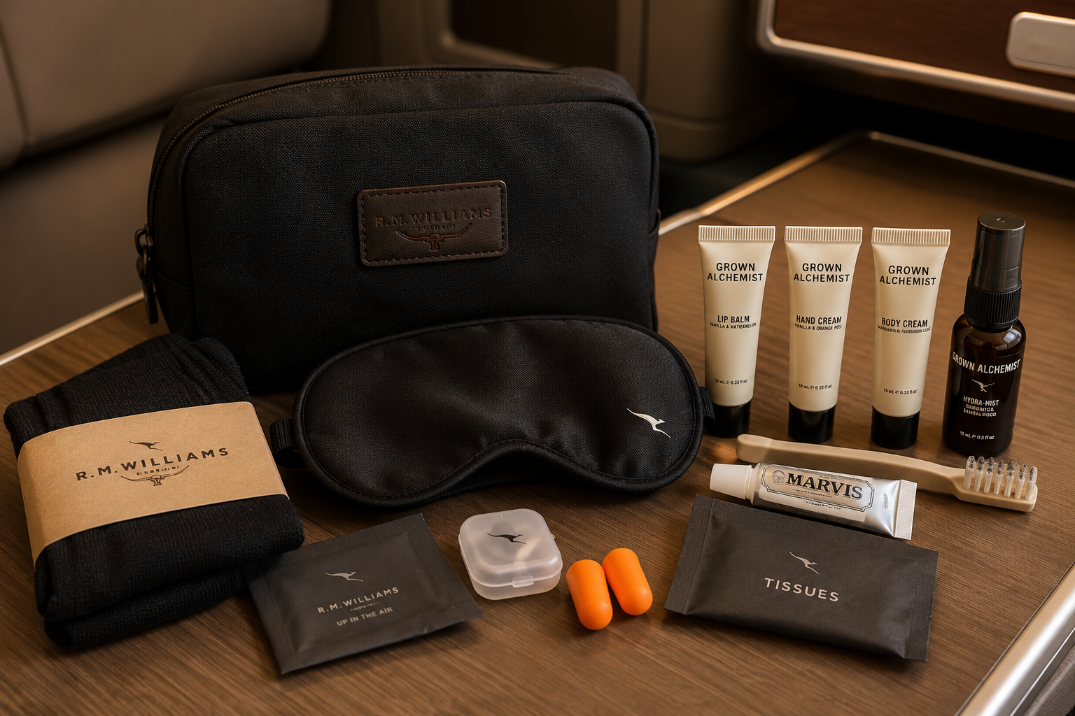 Qantas-style business class amenity kit with skincare products, sleep mask, socks, earplugs, toothbrush, and toothpaste on a tray table.