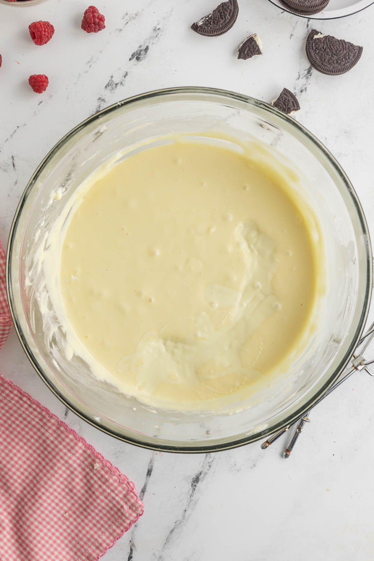 melted white chocolate added to cheesecake mixture in bowl 