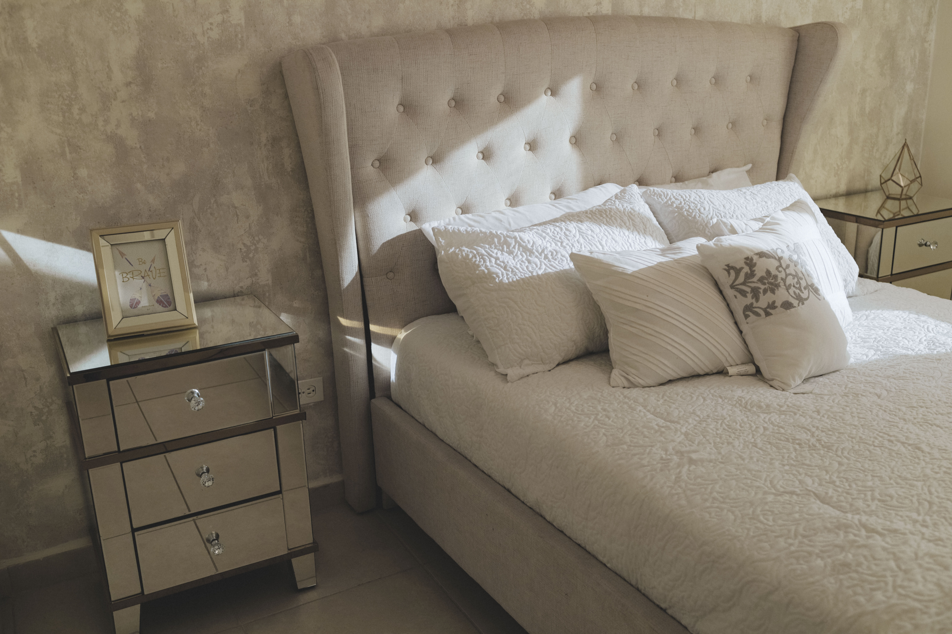 neutral bed and bedding with mirrored nightstands