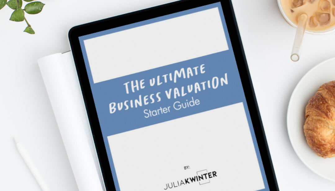 Tablet displaying "The Ultimate Business Valuation Starter Guide" surrounded by coffee and a croissant