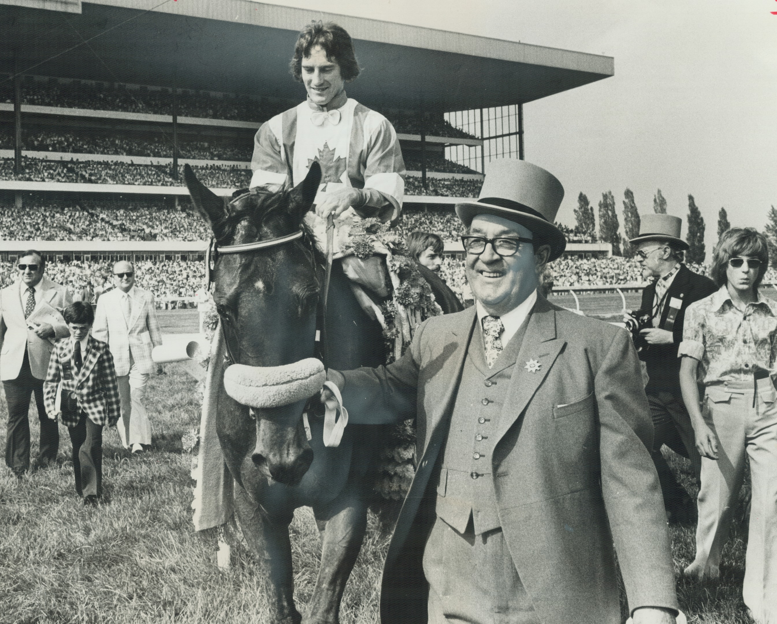 Delighted owner J. Louis Levesque of Montreal leads 1975 Queen's Plate winner L'Enjoleur and jockey Sandy Hawley to winner's circle at Woodbine Racetrack.