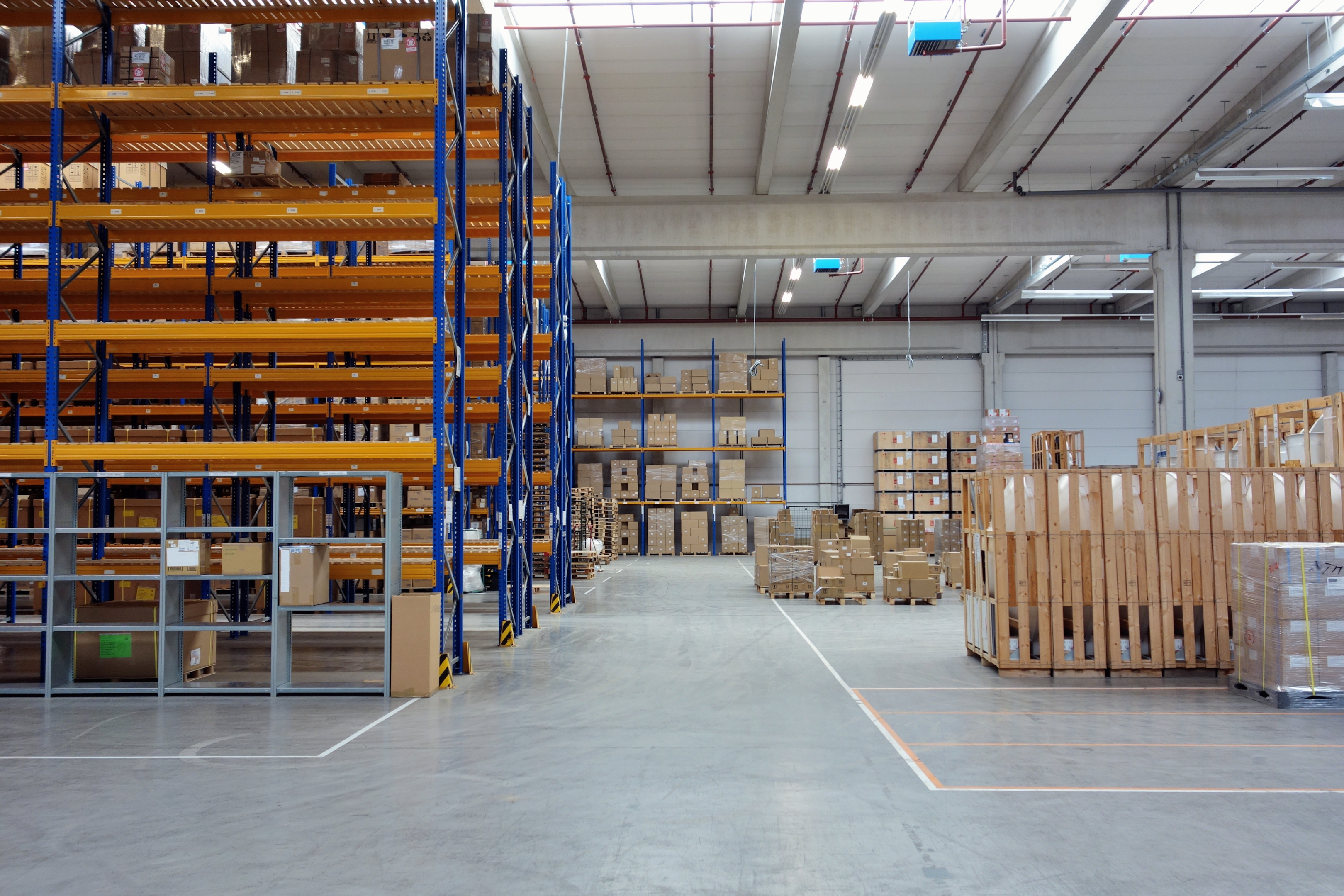 This is a photo of a warehouse with empty shelves on the left and pallets to the right.