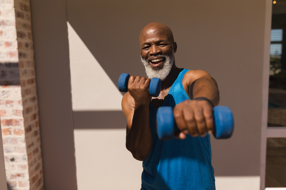 Older man with grey beard exercising with dumbbells