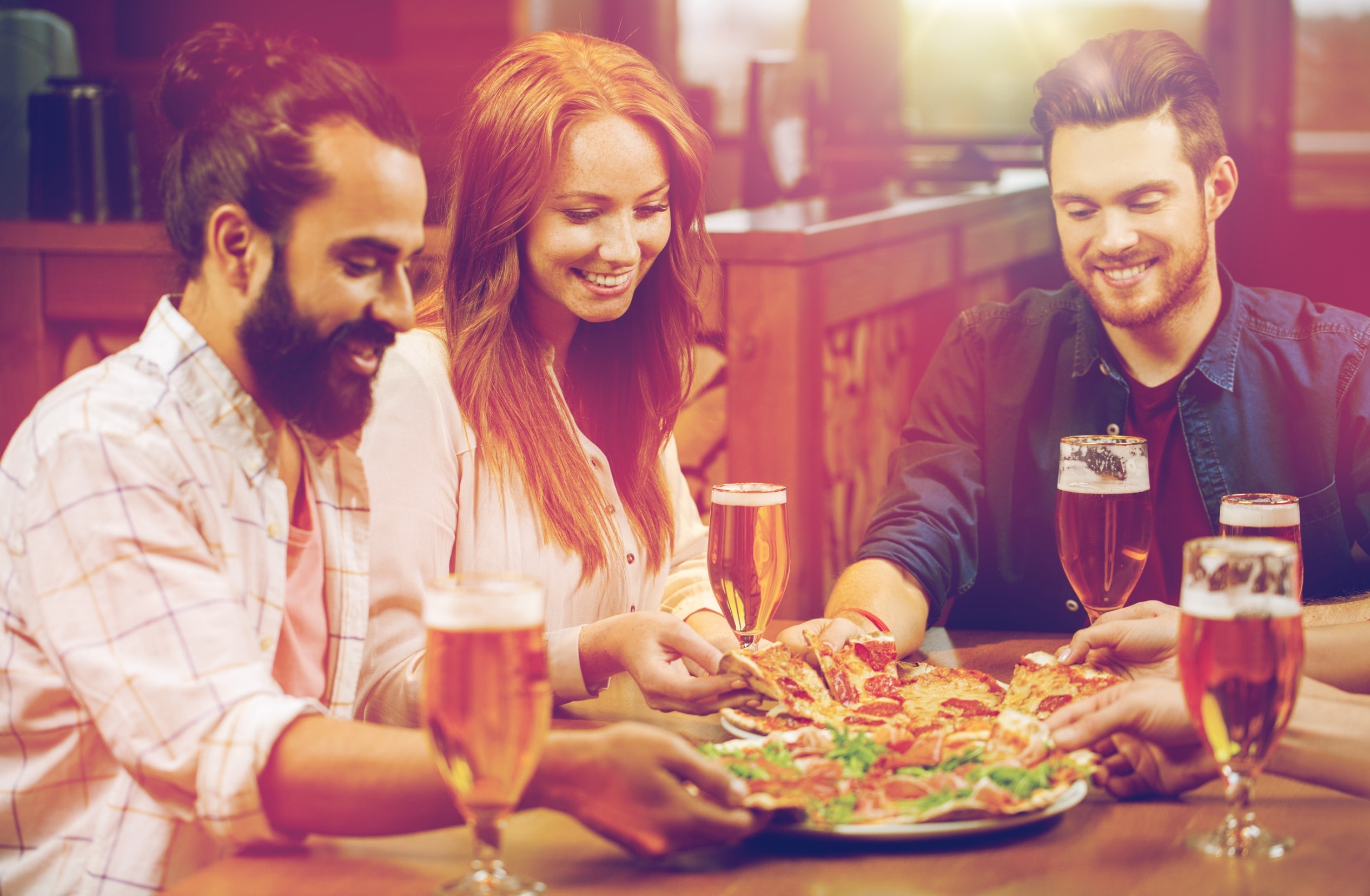 A group of people eating food and drinking beer at a pub