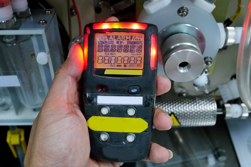 Installateur verwendet ein Gaslecksuch Gerät mit Warnleuchten während der Wartung einer Heizungsanlage, Sicherheitsüberprüfung im Fokus