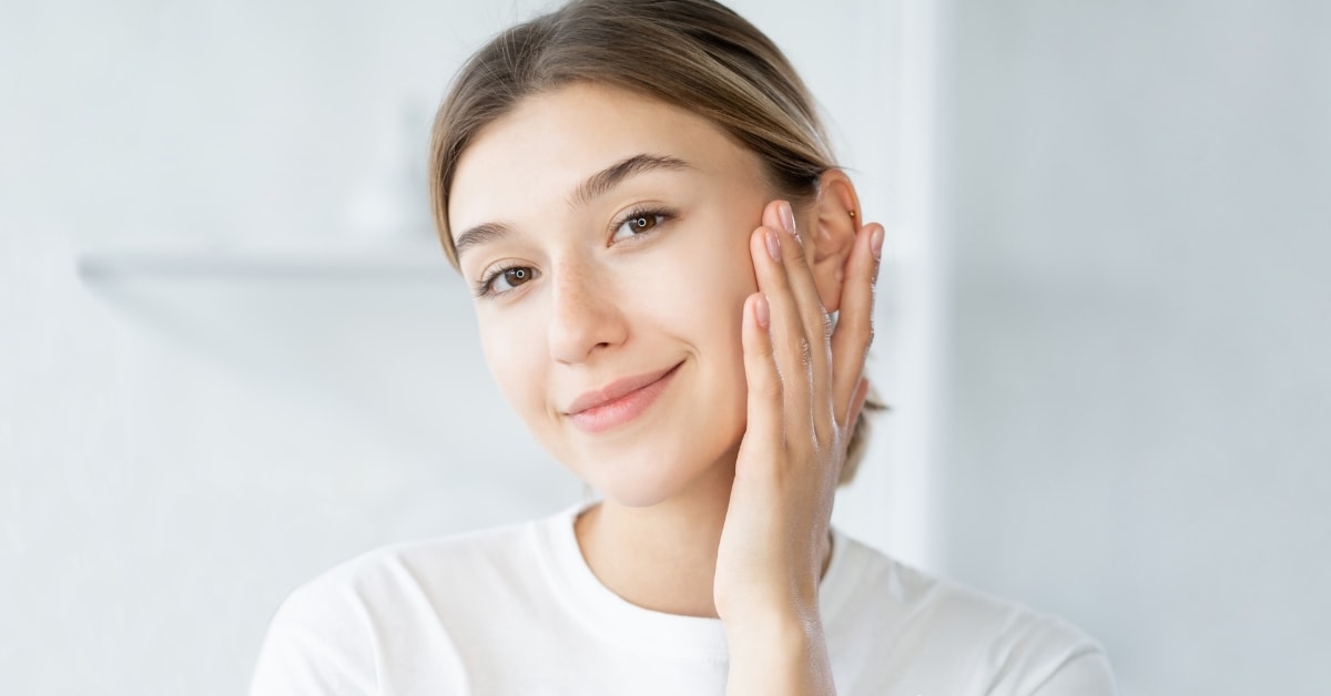 Young woman with glowing skin touching her face, highlighting the benefits of tax optimization.