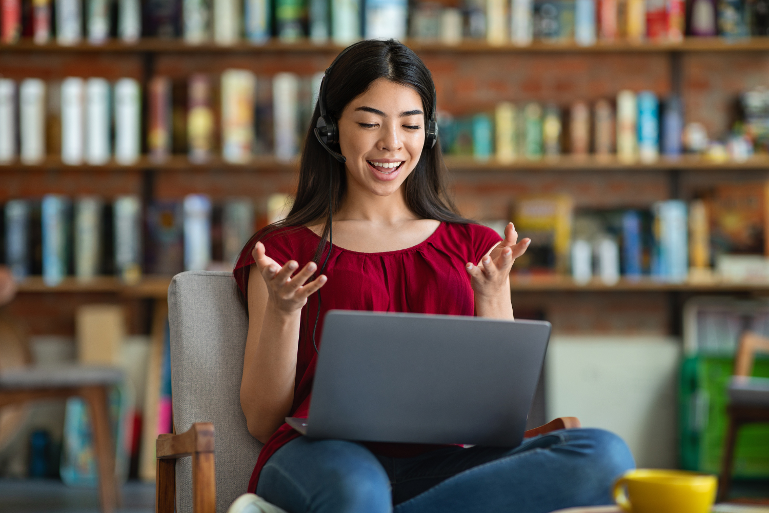 Woman with earphones smiling on her laptop while talking.