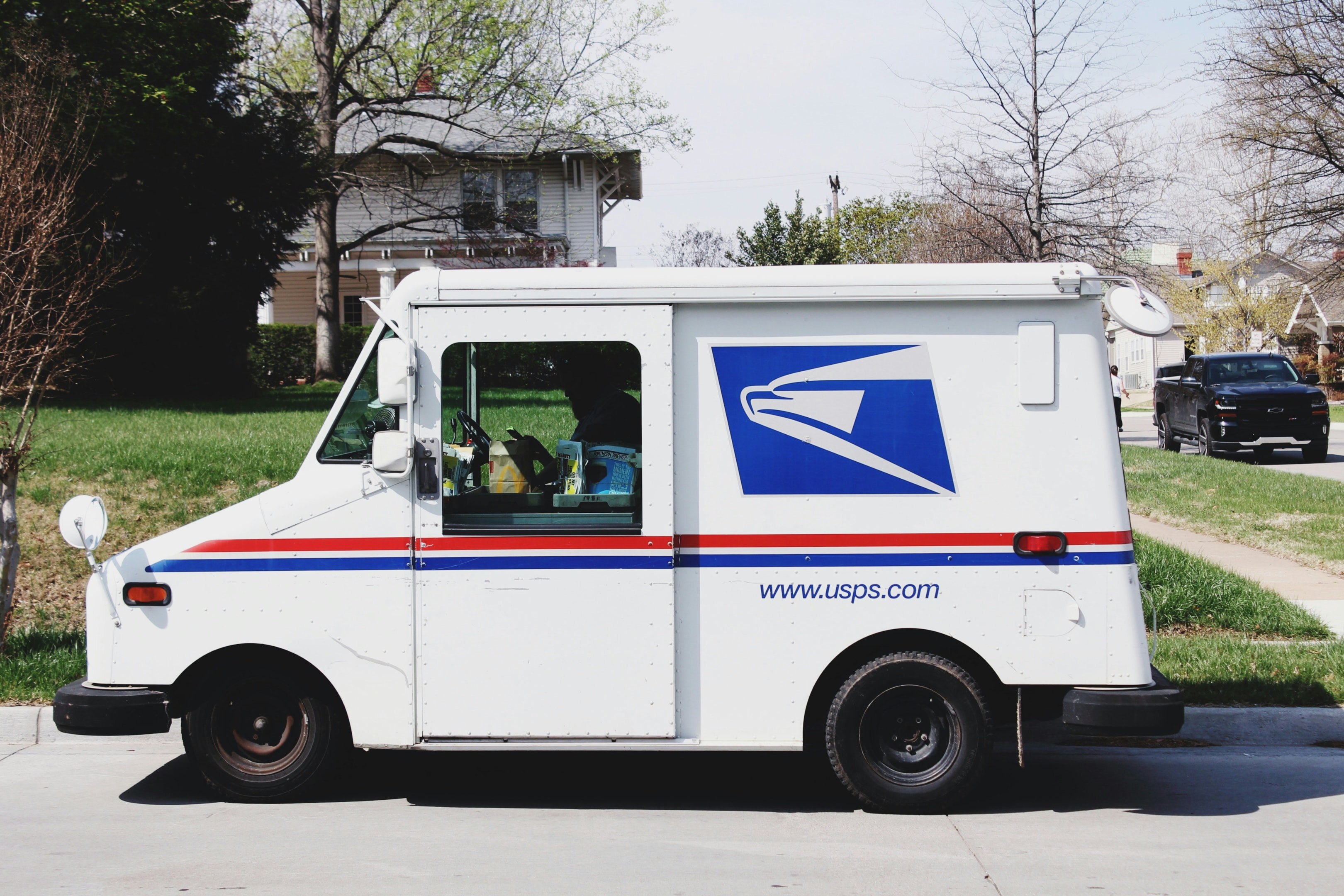 USPS mail truck delivers mail to distressed house. 