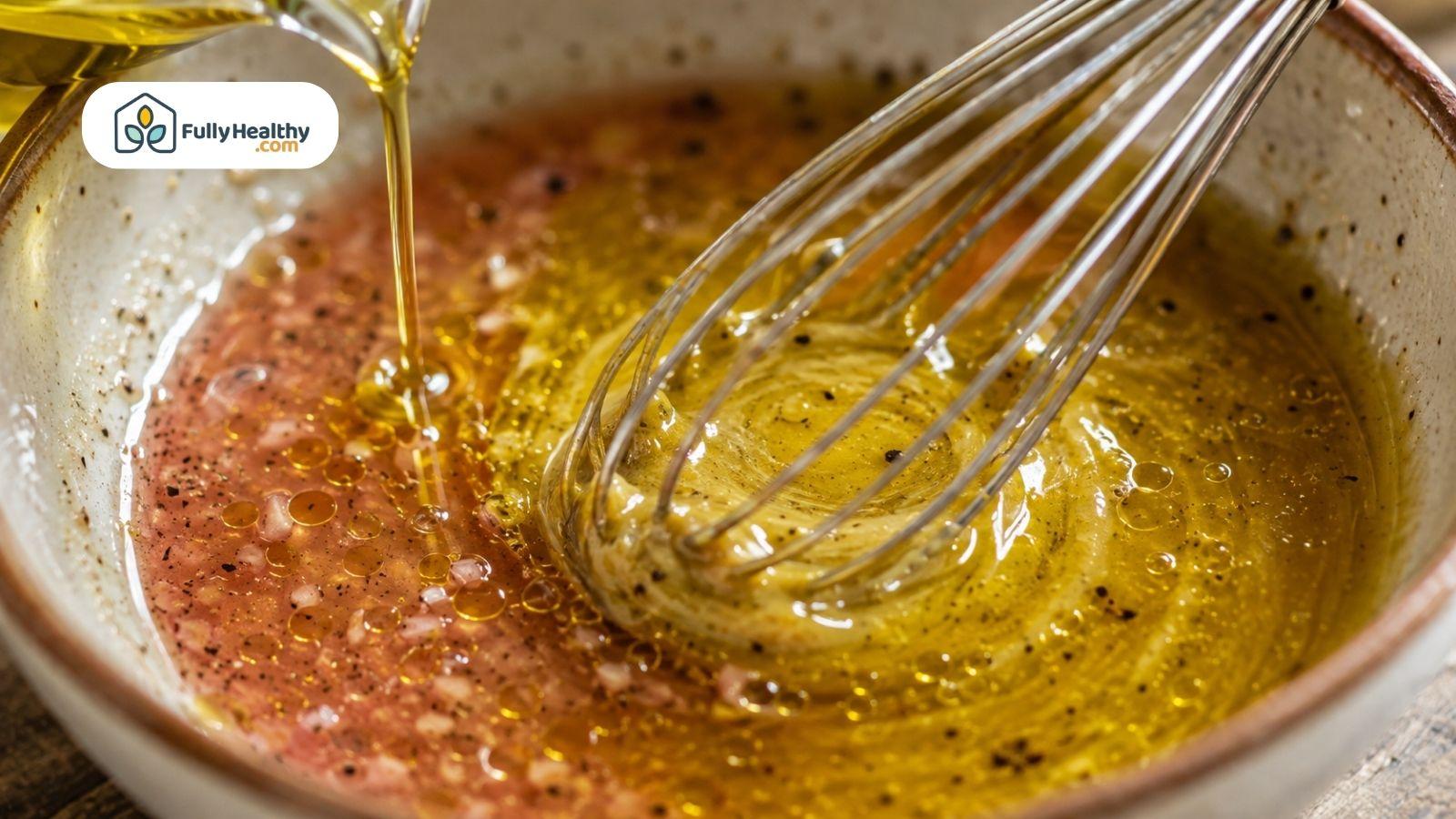 Olive oil whisked into vinegar to create homemade vinaigrette dressing.