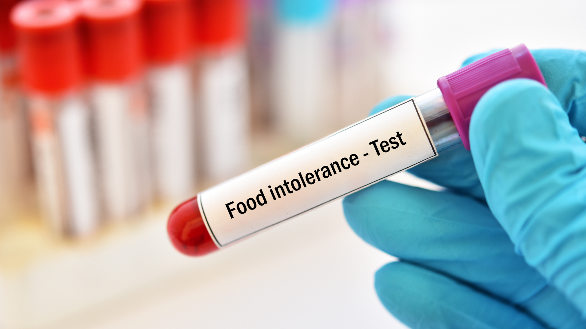 gloved hands holding a test tube with "food intolerance - test" on it