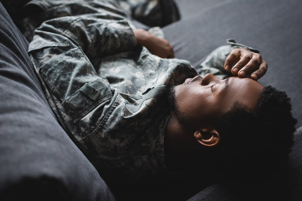 soldier in military uniform sleeping in sofa at home
