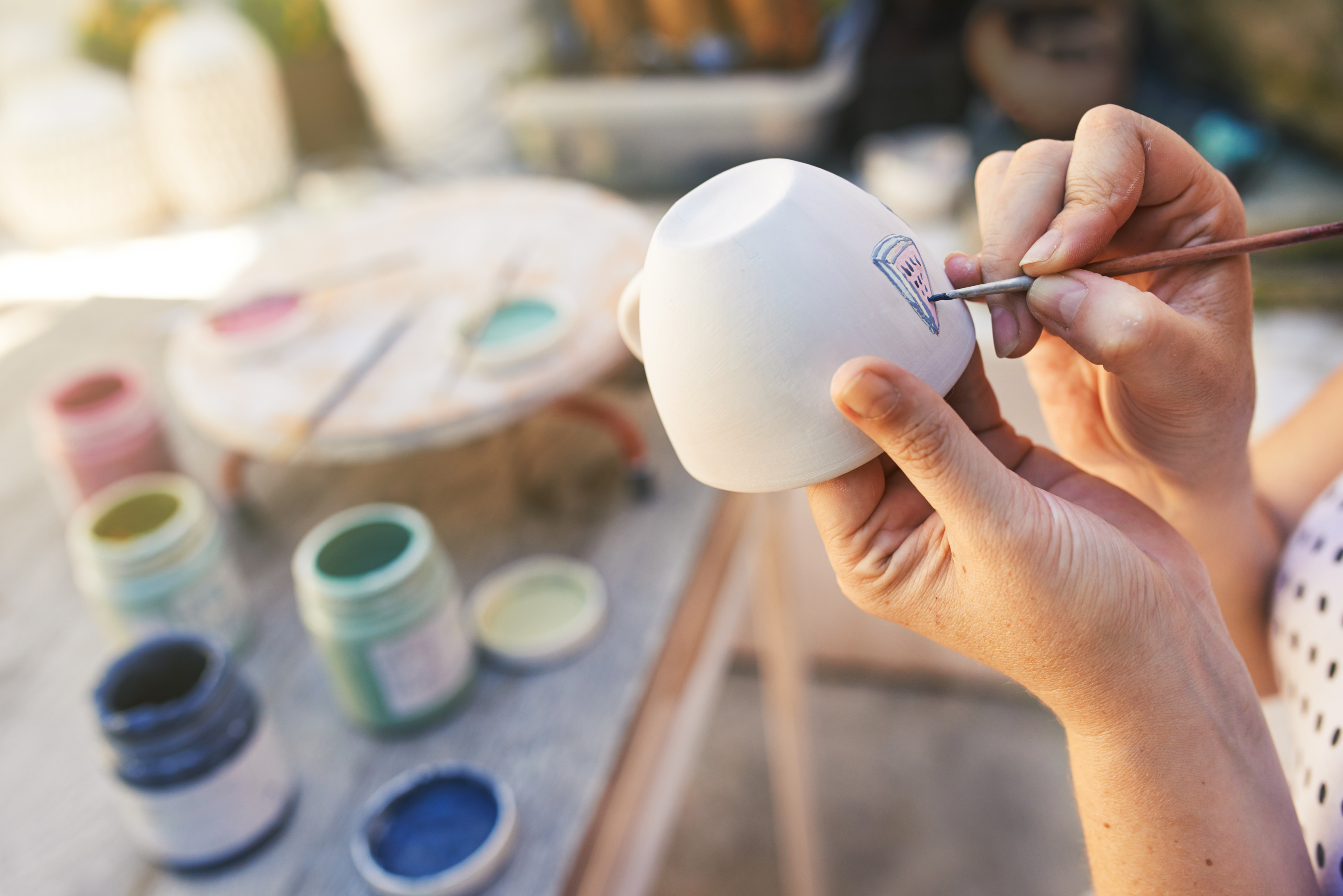 A person painting on a cup