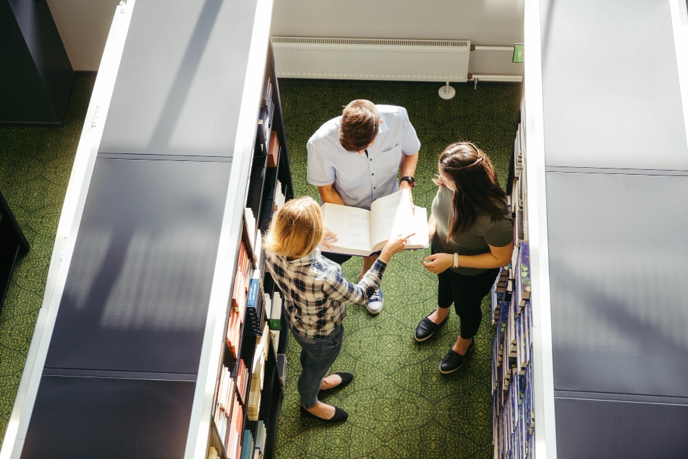 Classmates with book in library covered by the public address system and mass notification system.