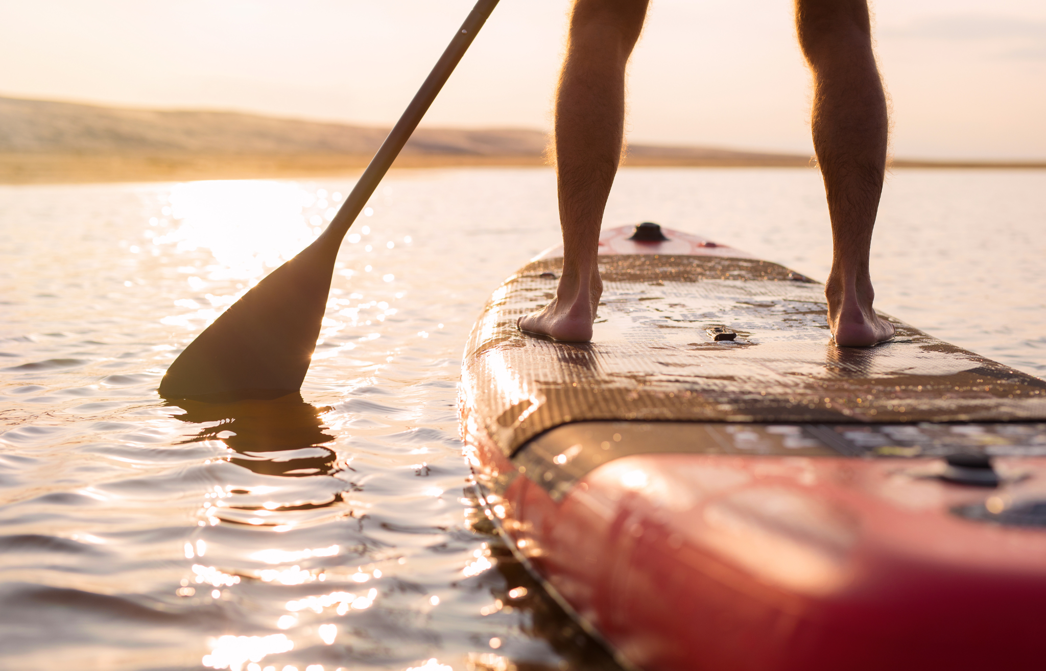 Person paddle boarding at sunset - Adventure Wise Travel Gear
