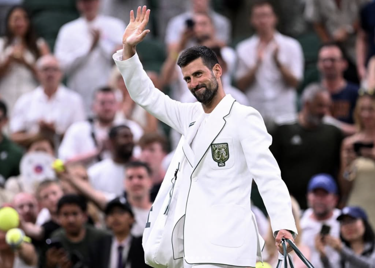 Novak Djokovic walking onto Centre Court sporting his white Lacoste jacket with green piping. Image obtained from Instagram..