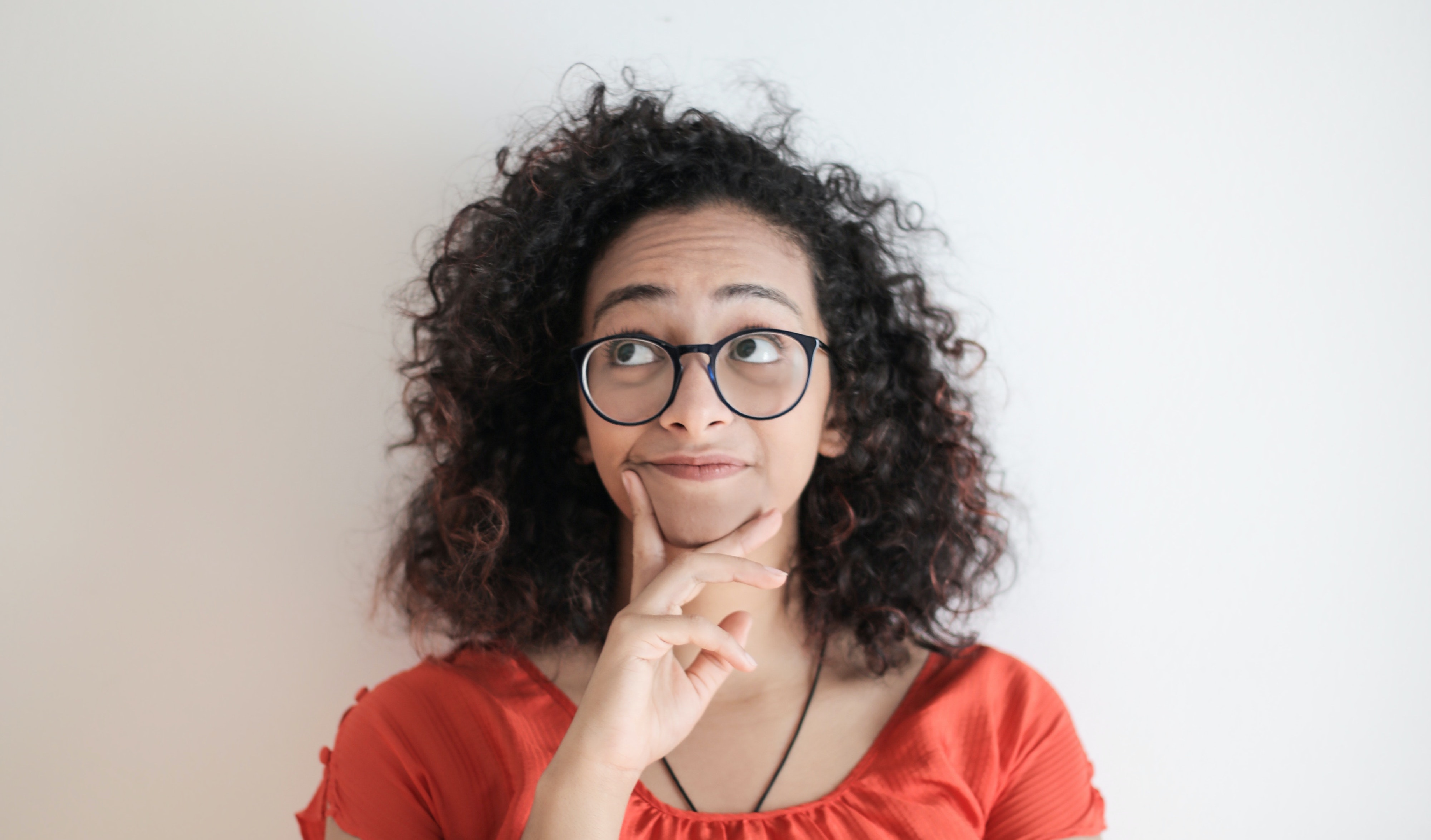 Woman wearing glasses and a red shirt, thinking