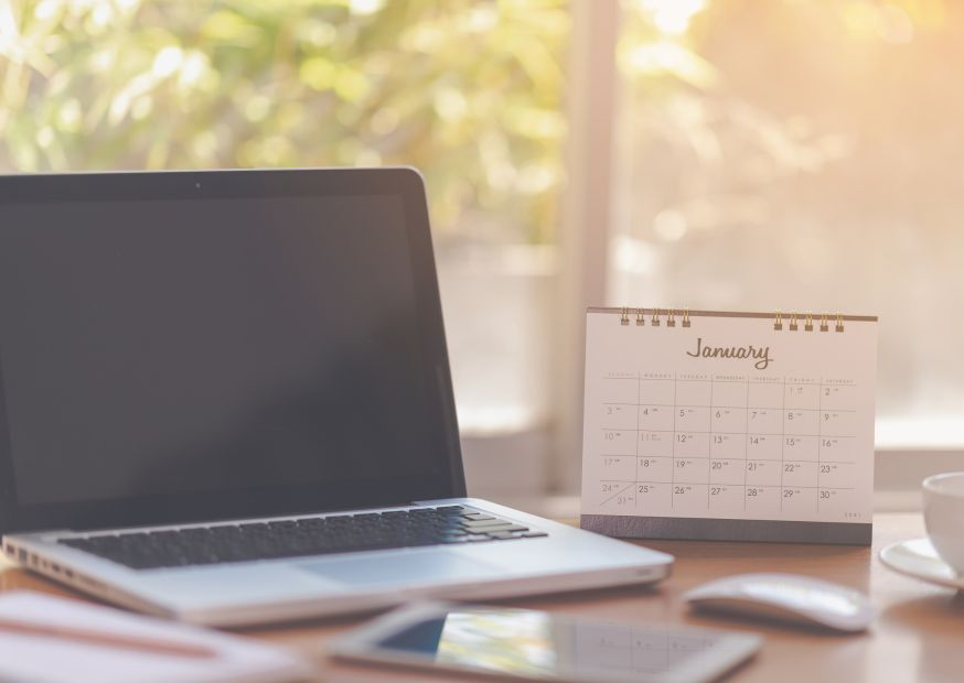 A calendar, laptop, and notes on the table