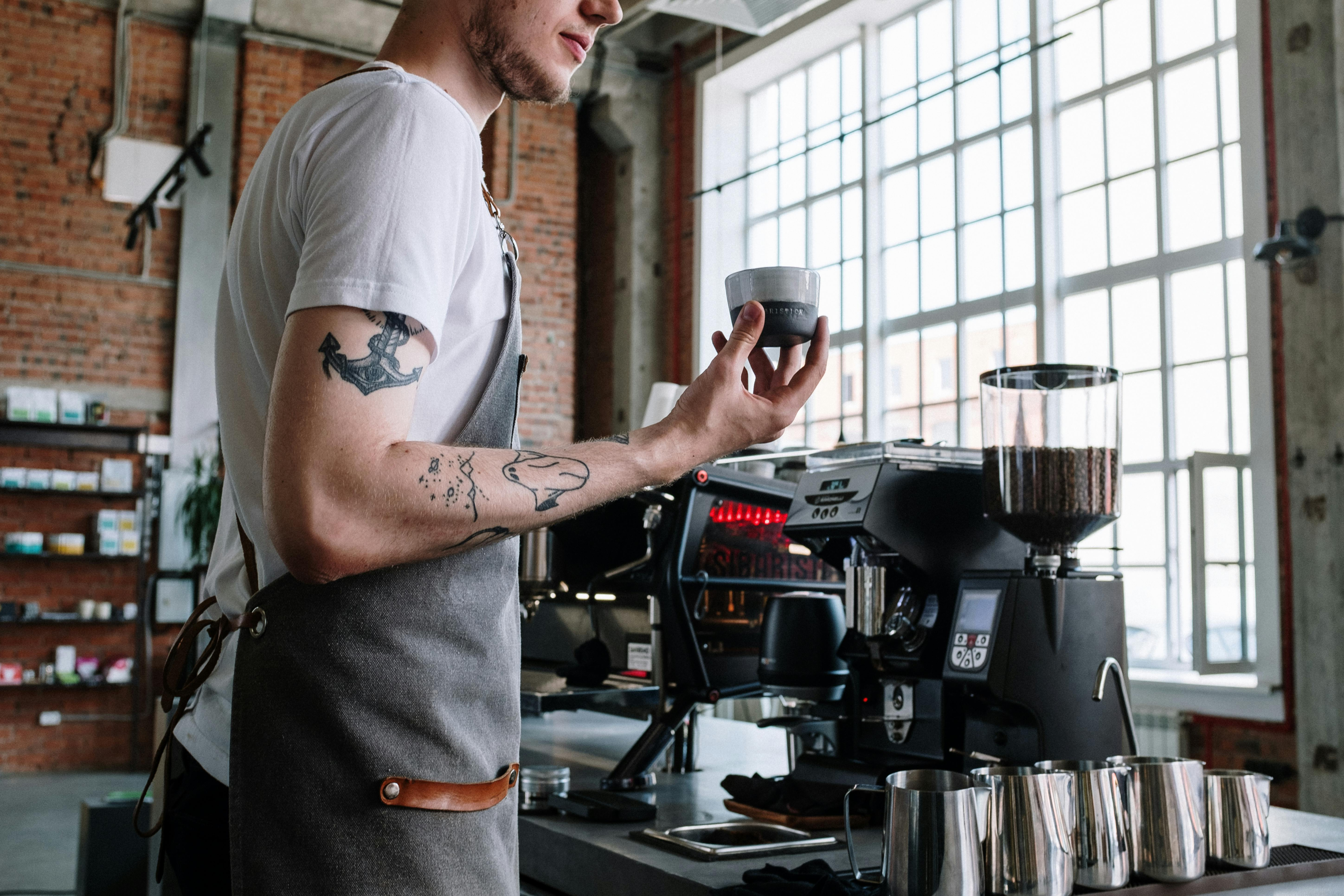 male barista operating an electric coffee grinder