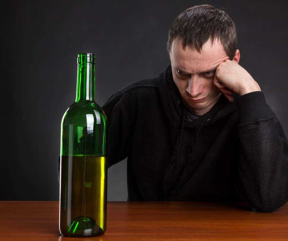 A person looking at a bottle of alcohol with a concerned expression