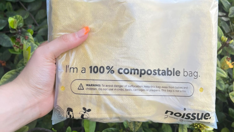 Hand holding a compostable packaging bag with eco-friendly and safety warnings