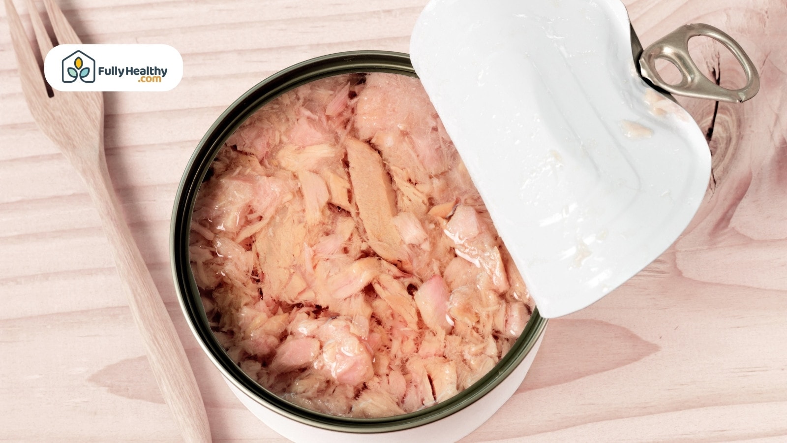 Open can of tuna flakes with soft pink texture on wooden table