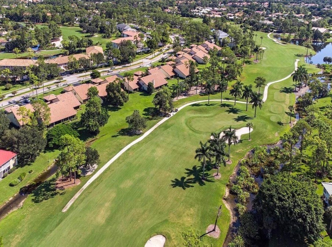 An aerial view of the Lely Country Club golf course in Naples, Florida, showcases a lush landscape filled with palm trees and serene water features, inviting residents and visitors to enjoy the beauty of this private golf area. The image highlights the well-planned layout of the course, surrounded by beautiful homes in the Lely Resort community.