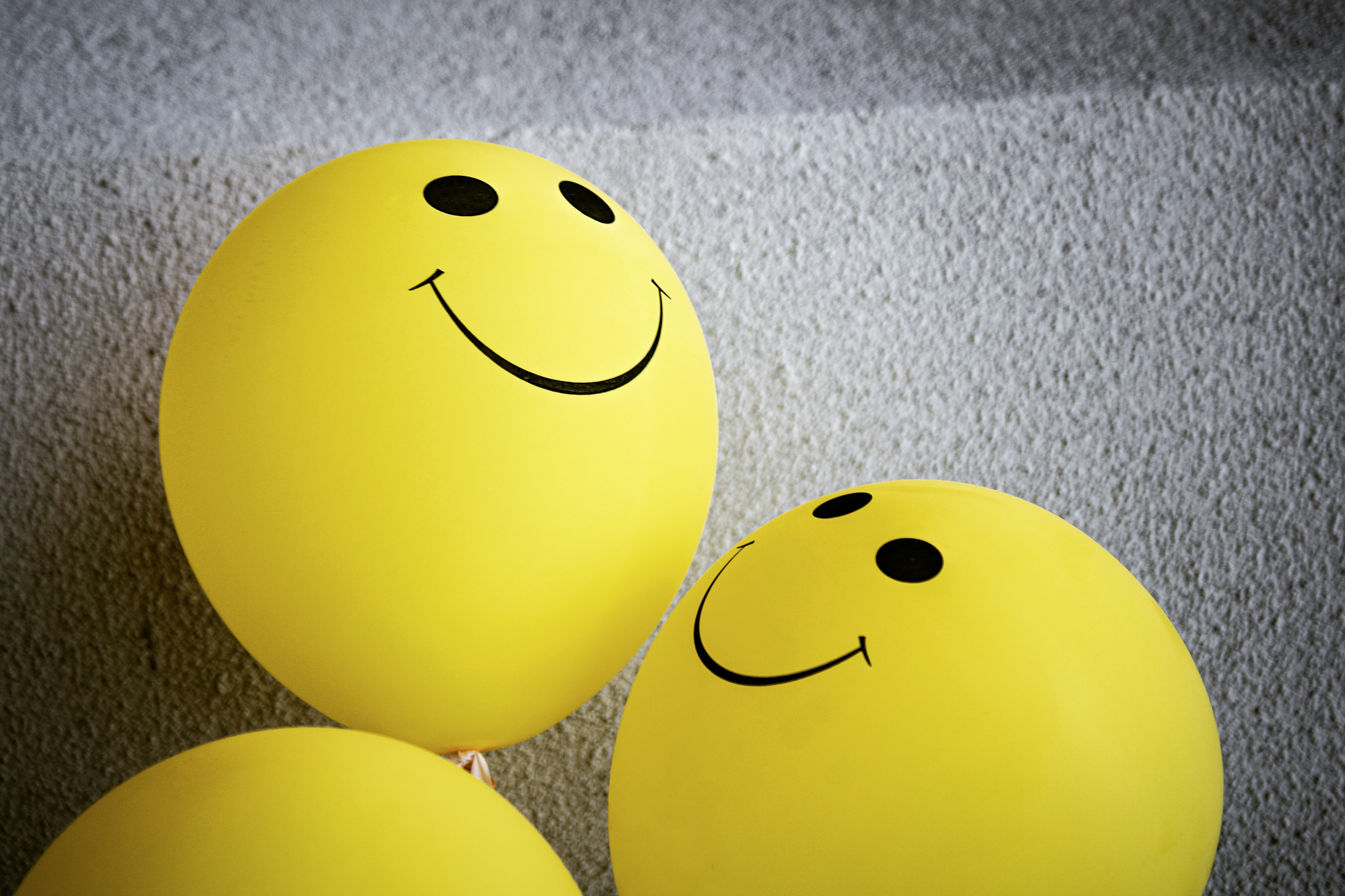 Two happy, yellow ballons with smiling faces.