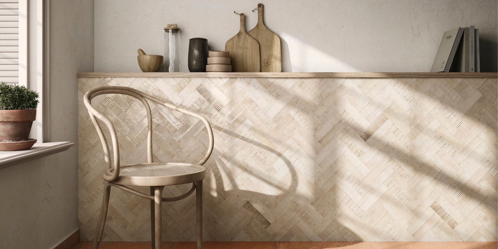 Beige textured tiles arranged in a herringbone pattern on a wall with a wooden chair and natural light.