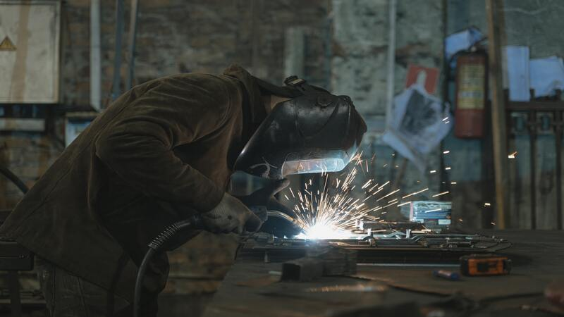 A welding expert welding welding by adjusting the workpieces in a welding fixture. 
